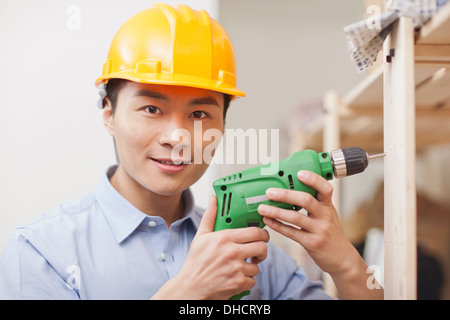 Portrait of young workman using electric drill in office,close-up Stock Photo