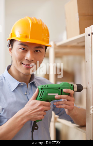 Portrait of young workman using electric drill in office,close-up Stock Photo