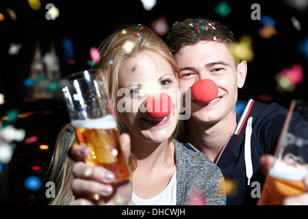 Germany, North Rhine Westphalia, Cologne, young couple with clowns noses toasting Stock Photo