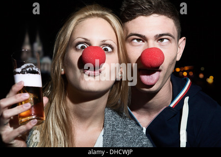 Germany, North Rhine Westphalia, Cologne, young couple with clowns noses toasting Stock Photo