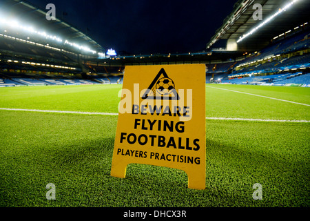 A view of Stamford Bridge, home to Chelsea football Club with a notice board warning of flying footballs Stock Photo