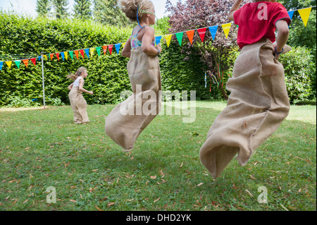 Children having a sack race in garden on a birthday party Stock Photo