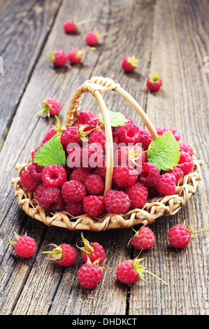 Raspberries in a wicker basket on wooden table Stock Photo