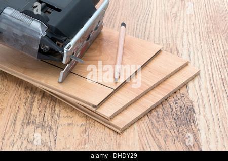 An electric jigsaw resting on some planks of wood effect laminate panels - studio shot Stock Photo