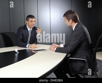 Two businessmen discussing tasks sitting at office table Stock Photo