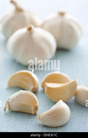 Three bulbs and six cloves of fresh white garlic on a table surface. Stock Photo