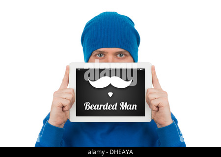 A young man holding in front of his face a tablet computer, on which are drawn a mustache and beard. Stock Photo