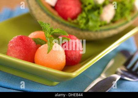 Refreshing cantaloupe and watermelon balls garnished with mint with a fresh salad in the back) Stock Photo