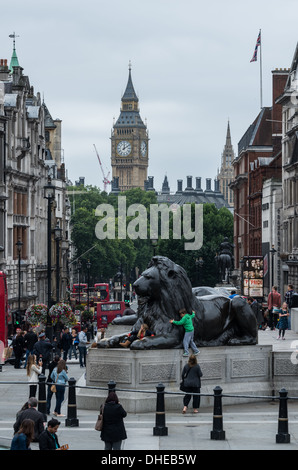 View from Trafalgar Square to the Houses of Parliament with Lion Statue prominent in foreground children playing Stock Photo