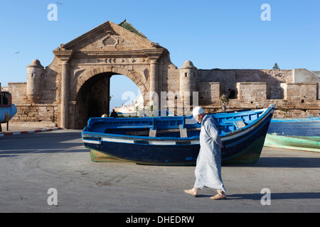 Old Muslim man walking below the old city gate and ramparts, Essaouira, Atlantic coast, Morocco, North Africa, Africa Stock Photo