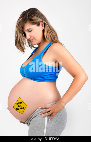 Beautiful pregnant woman posing in fitness clothes with baby on board sticker Stock Photo