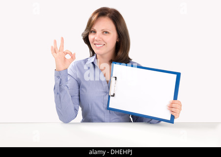 Smiling business woman is holding a blank clipboard and showing ok gesture, business concept Stock Photo