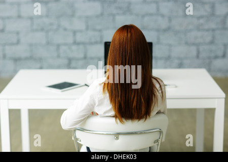 Picture from behind of a businesswoman sitting at her desk Stock Photo