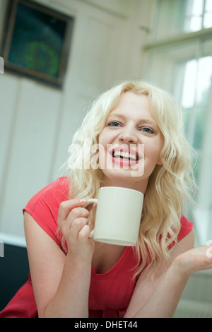 Young woman in conversation, holding a hot drink Stock Photo