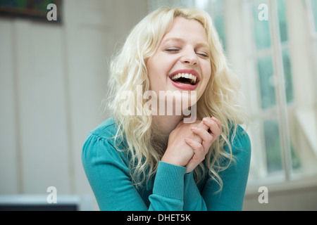 Happy young woman with eyes closed and hands together