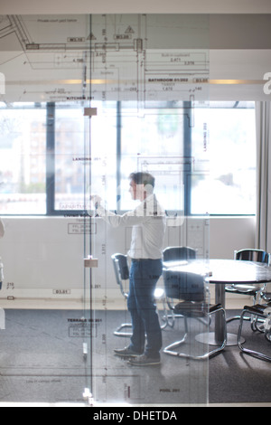 Man drawing architectural plans on glass wall Stock Photo