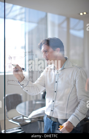 Man drawing architectural plans on glass wall Stock Photo