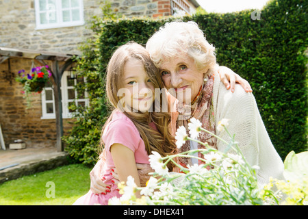 Portrait of grandmother and granddaughter with arms around each other Stock Photo