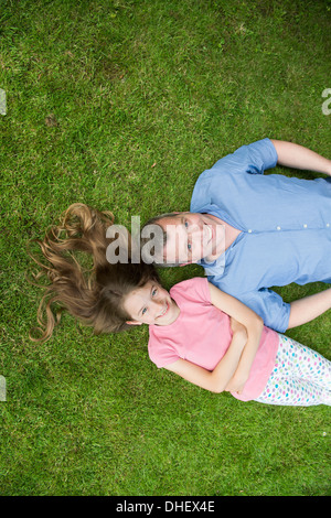 Father and daughter lying on grass Stock Photo