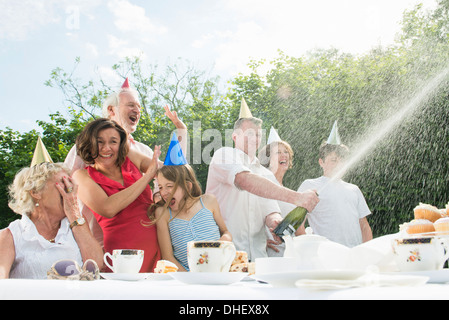 Family celebrating birthday, man opening champagne Stock Photo