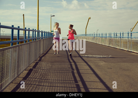 Young female joggers running on bridge Stock Photo