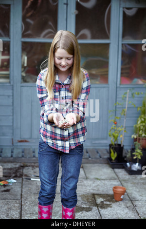 Girl in garden cupping seeds in hand Stock Photo