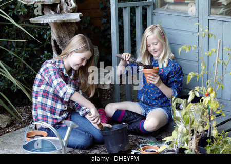 Two girls in garden planting seeds into pots Stock Photo