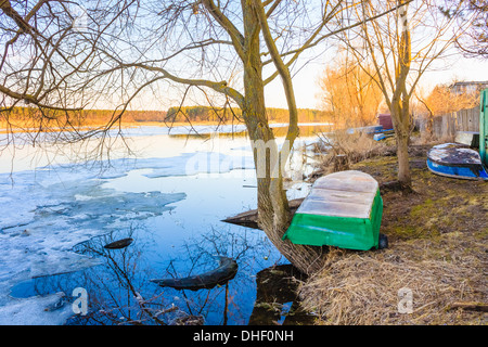 Spring landscape with flooded trees and old boats on coast. Russian nature, early spring. Stock Photo
