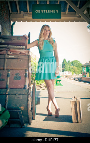 Young pretty blond girls waiting at a vintage railway station Stock Photo