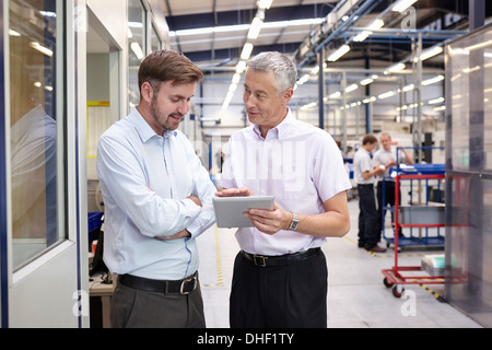 Manager and worker looking at digital tablet in engineering factory Stock Photo