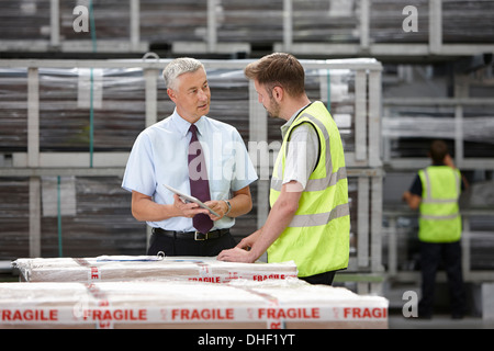 Warehouse worker and manager discussing order in engineering warehouse Stock Photo