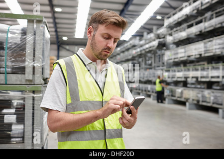 Portrait of worker using mobile phone in engineering warehouse Stock Photo