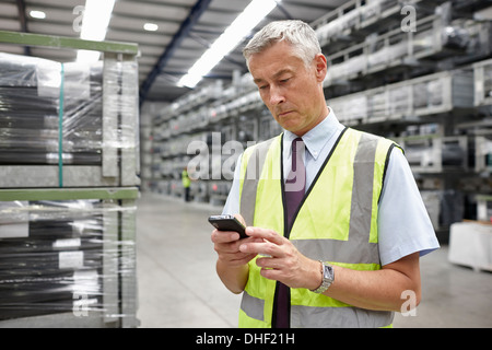 Portrait of manager using mobile phone in engineering warehouse Stock Photo