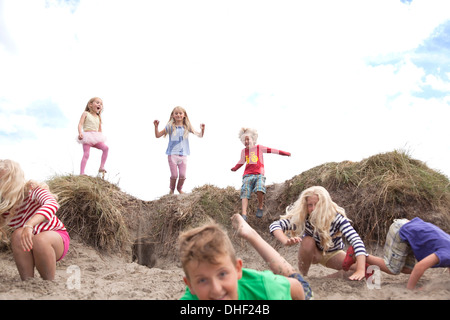 Group of children jumping off sand dunes, Wales, UK Stock Photo