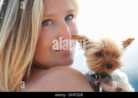 Mature woman holding pet dog, looking over shoulder