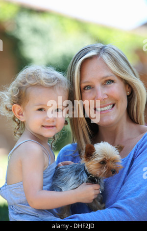 Portrait of mother holding young daughter and dog Stock Photo