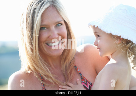 Portrait of mother holding young daughter wearing sunhat Stock Photo