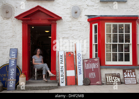 Woman sitting in antique shop doorway Stock Photo