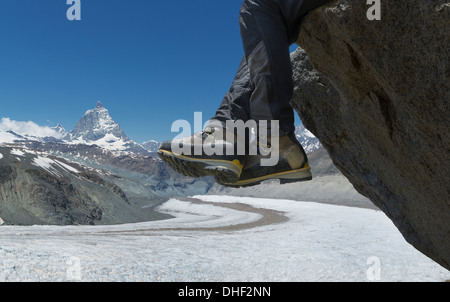 Man sitting on rock by the Matterhorn, Zermatt, Canton Wallis, Switzerland Stock Photo