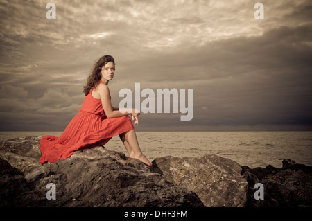 Brunette model on rocky beach during a storm Stock Photo