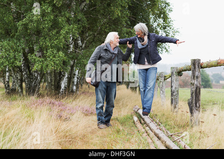 Senior couple, woman balancing on logs Stock Photo