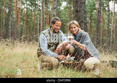 Mid adult couple foraging for mushrooms in forest Stock Photo