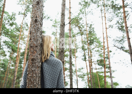 Mid adult woman leaning against tree, low angle Stock Photo