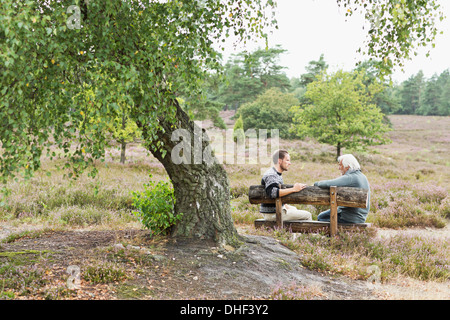 Senior man and mid adult man sitting on bench