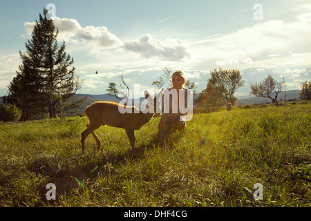 Young woman in field with fawn Stock Photo