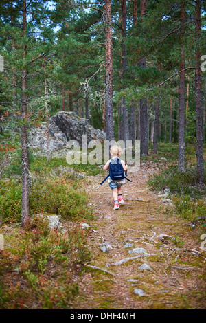 Rear view of girl carrying rucksack through forest Stock Photo