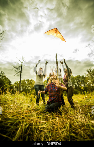Five young women flying kite in scrubland Stock Photo