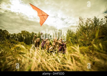 Five young women having fun with kite in scrubland