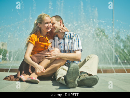 Young couple sitting next to city fountain Stock Photo