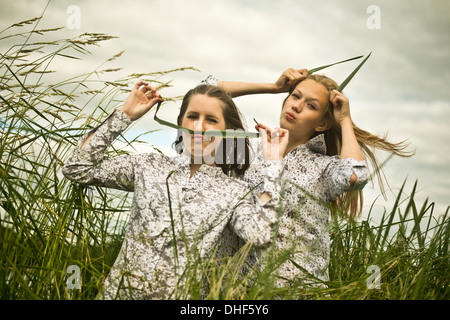 Two young women making faces with grass